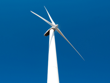 Een foto van een windmolen, met een blauwe lucht op de achtergrond