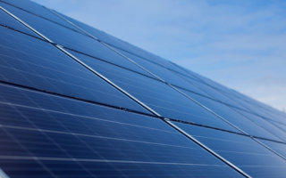 Een foto van zonnepanelen met een blauwe lucht op de achtergrond.